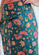 Side image of model wearing green A line skirt with piped details, pockets and side zipper.