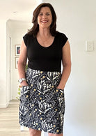 Woman wearing a black t-shirt and 100% cotton skirt with pockets indoors.