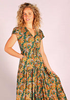 Model wearing green based floral rayon sundress with buttoned bodice and hidden side pockets