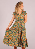 Model wearing green based floral rayon sundress with buttoned bodice and tulip sleeves