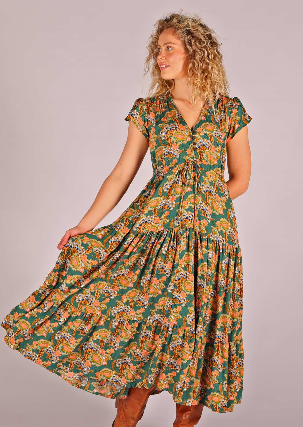 Model facing to the side and holding skirting of green based floral rayon sundress with full skirt