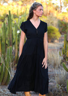 Model wears black rayon maxi dress with tulip sleeves, V-neckline and voluminous skirt