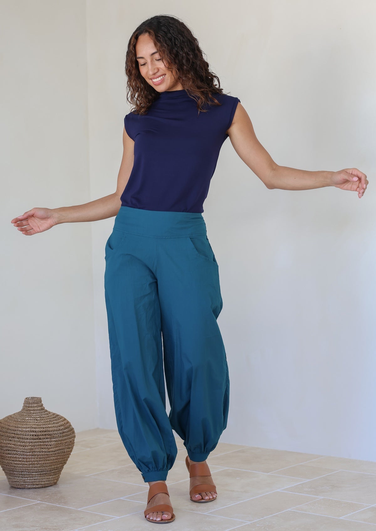 Woman posing in 100% cotton wide leg pants with cuffed ankles, a shirred back waist, and pockets in deep teal color