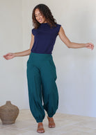 Woman posing in 100% cotton wide leg pants with cuffed ankles, a shirred back waist, and pockets in deep teal color