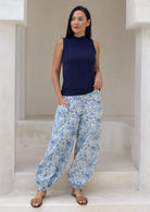 Woman wearing a navy sleeveless top and blue cotton floral pants, with her hand in pocket