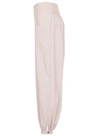 Side view of relaxed fit white cotton pants with pockets, elastic waist and buttoned ankles