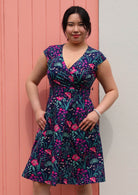  Woman in Alice Dress Dianthus retro style 100% cotton navy blue floral with cross over bodice and pockets fit and flare style dress thumbs in pockets