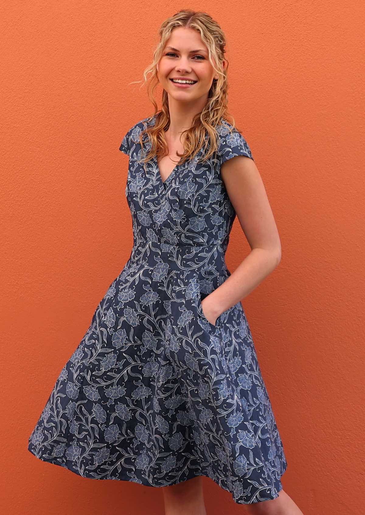 Model standing in front of orange wall with hands in pockets wearing 100 percent cotton retro style dress