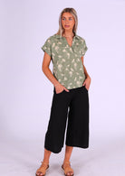 Woman stands in relaxed fit cotton top with rolled cuffs and a collar, paired with cotton 3/4 length pants