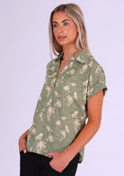 Model wears short sleeve relaxed fit cotton top with V-neckline and collar, in cream floral with pale green base