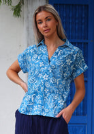 Woman wears relaxed fit cotton short sleeve top in beautiful blue floral print