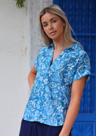 Woman in cotton short sleeve top with V-neckline and collar and rolled cuffs