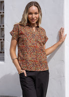 Woman wearing an earthy tone with rust base printed shirt with a collar and V-neckline