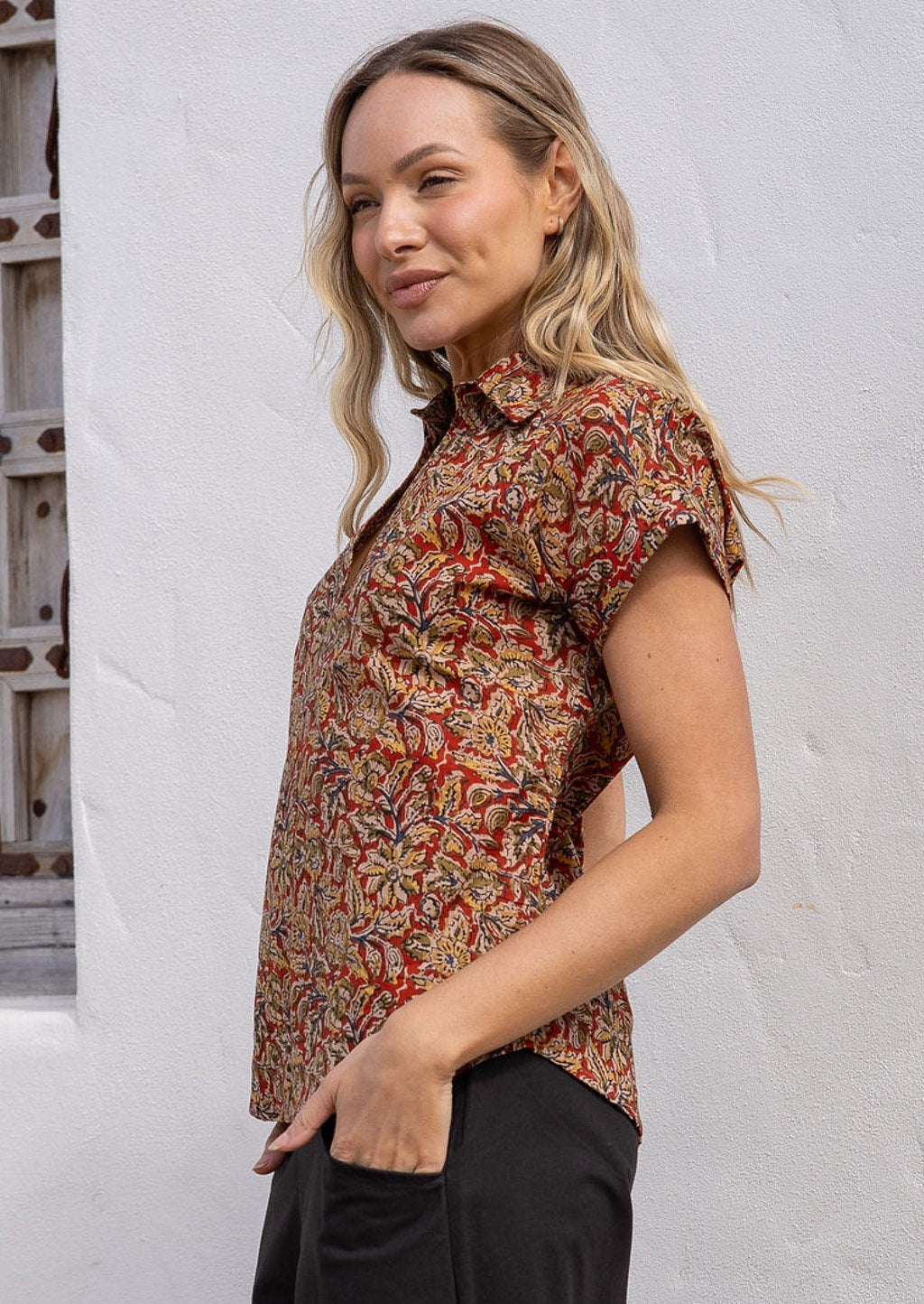 Woman wearing an earthy toned Indian print cotton shirt with a collar, with hands in pockets of pants