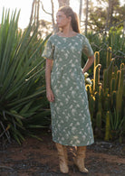 Woman wears cotton midi length relaxed fit dress with short sleeves and pockets