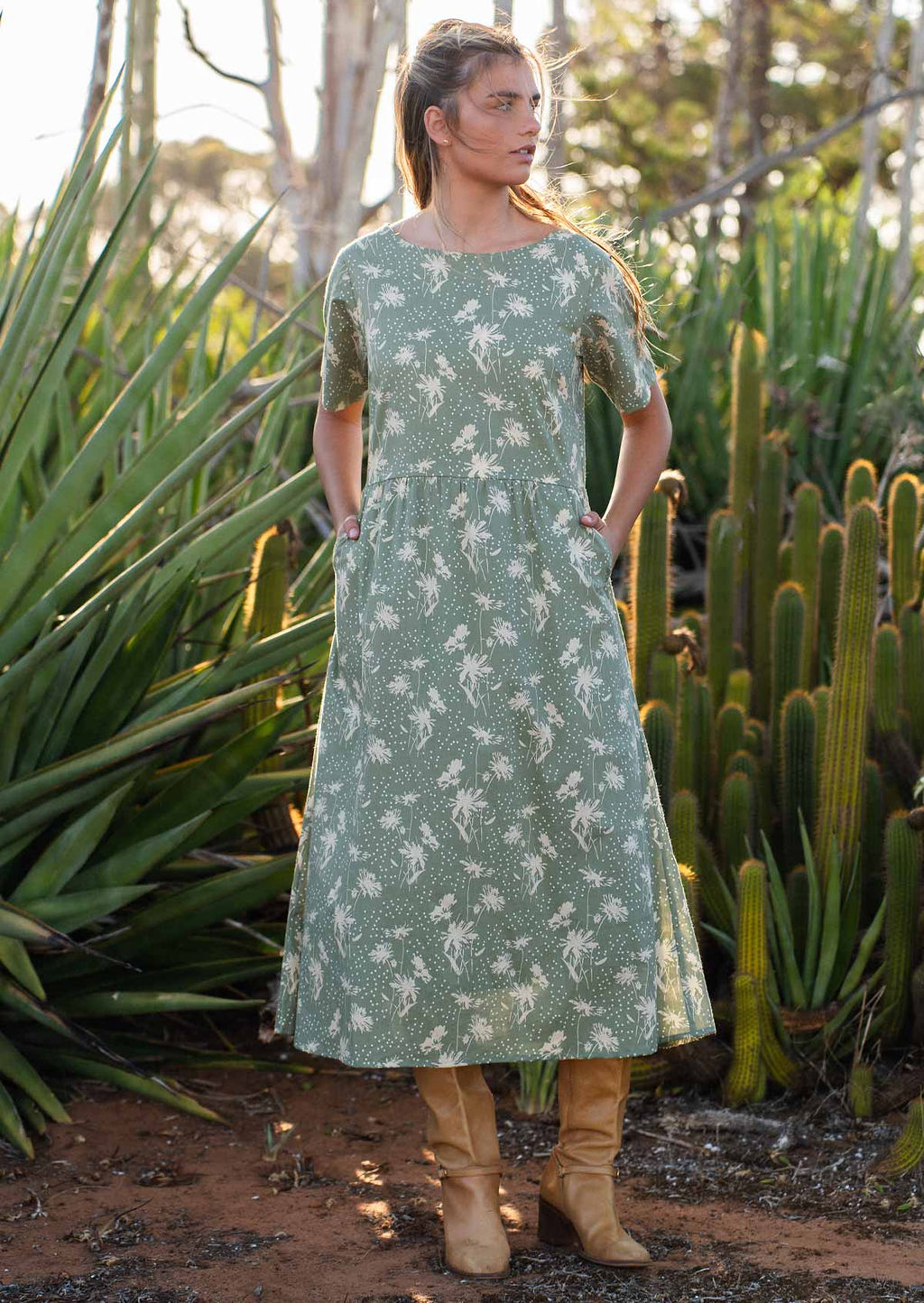 Model stands in front of cactus garden in pale green based cotton relaxed fit midi length dress