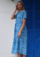 Woman stands sideways in cotton midi length relaxed fit dress with short sleeves