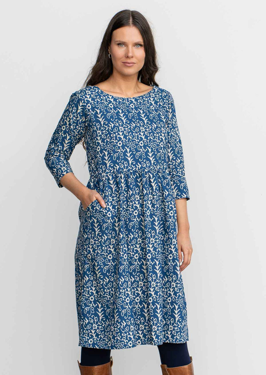 Woman in blue cotton, knee length sundress with sleeves,  with hand in pocket