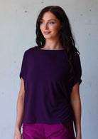 woman with dark hair wearing purple t-shirt and purple corduroy pants