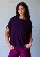 woman with dark hair wearing purple rayon batwing t-shirt and purple corduroy pants