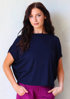 Woman wearing navy blue batwing t-shirt over purple corduroy pants