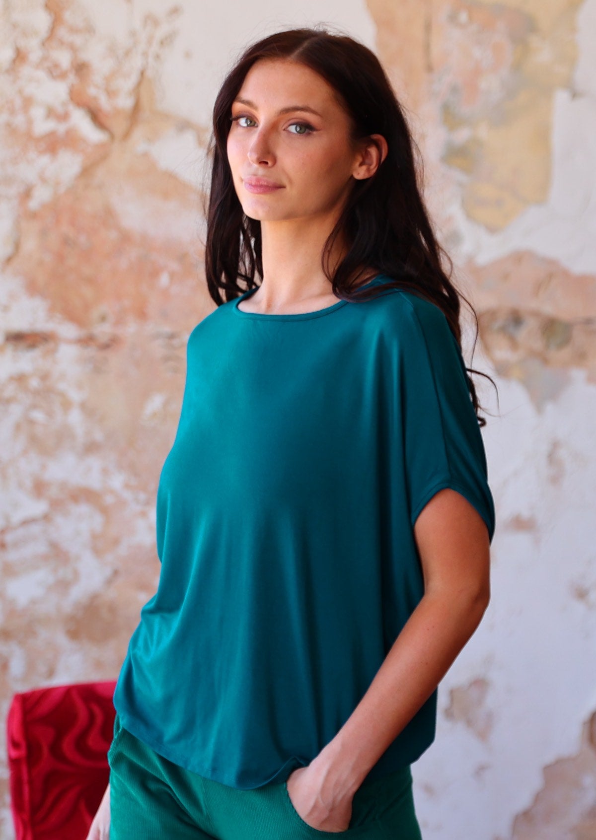 woman in teal coloured rayon batwing t-shirt with corduroy pants 
