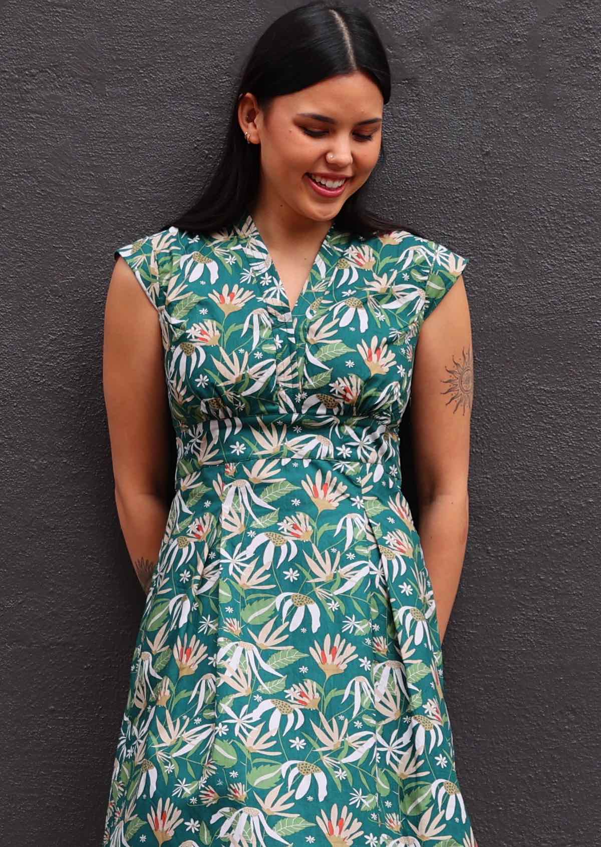 Close up of model wearing floral dress with dark green background 100 percent cotton retro style 