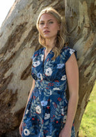 Model leans on tree in retro cotton dress with two box pleats in front and V-neckline