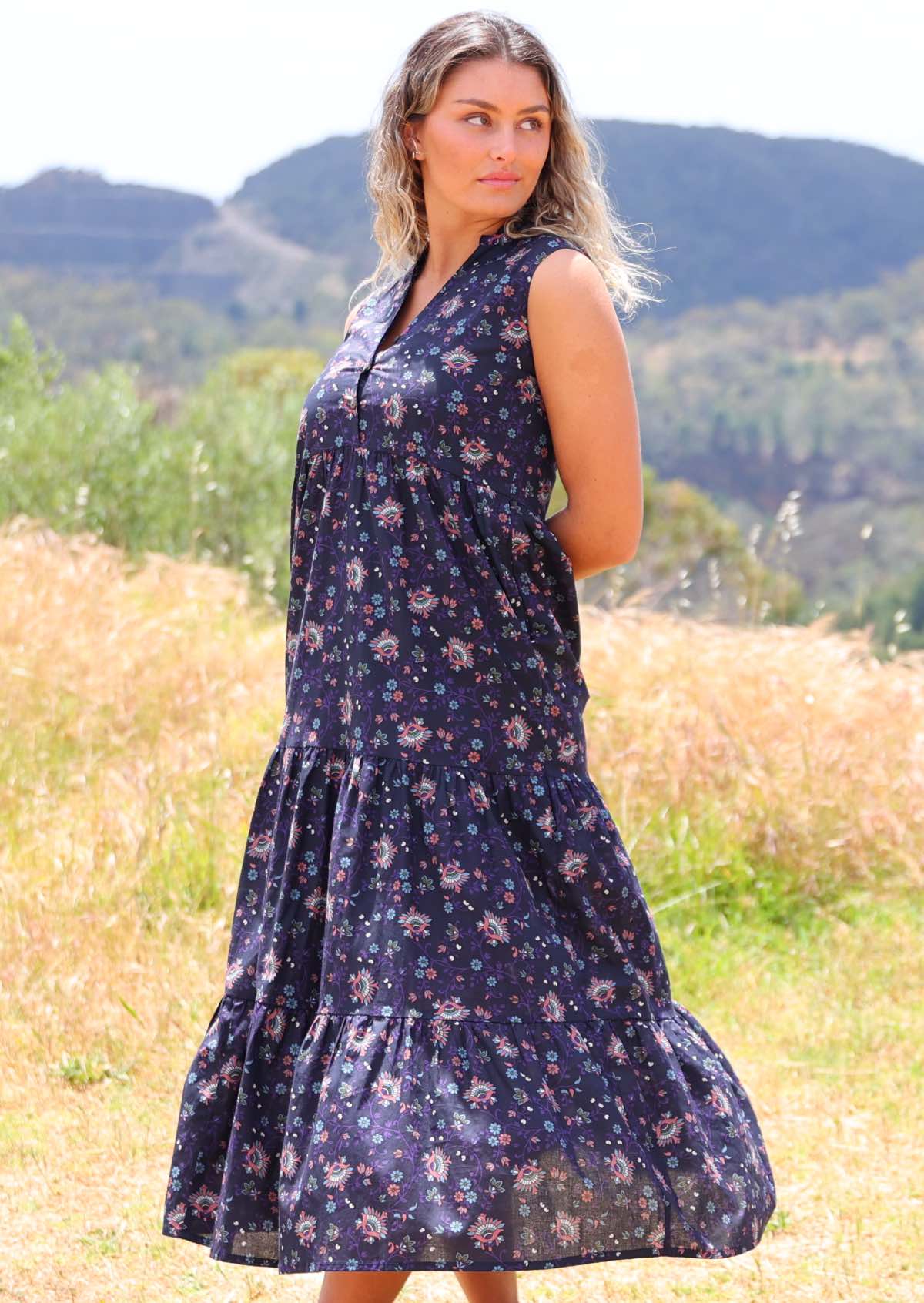 Model poses in cotton floral print sleeveless maxi dress with flowing three tiered skirt