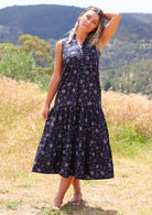 Model wears sleeveless cotton maxi dress in floral print on a dark base