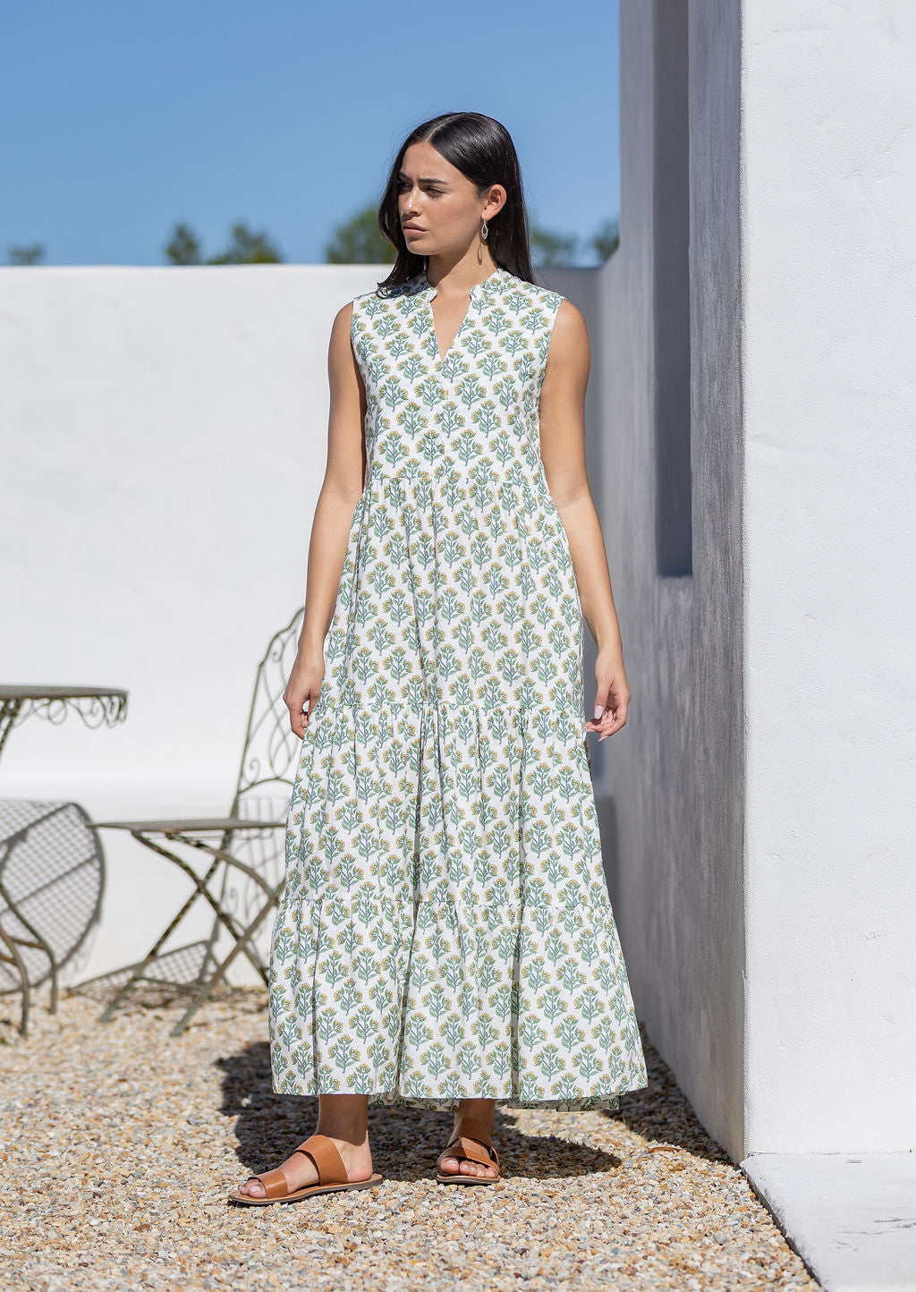 Woman wearing a sleeveless white cotton maxi dress with a floral pattern outdoors.