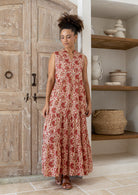 Model wearing a cotton three tiered maxi sleeveless dress and buttoned bodice in cream based floral print.
