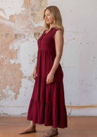 Woman wears sleeveless double cotton maxi dress with three tiered skirt in deep red