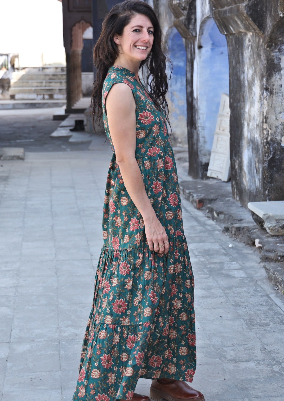 Model standing sideways wearing a gorgeous green floral printed maxi dress with v neckline and pockets.