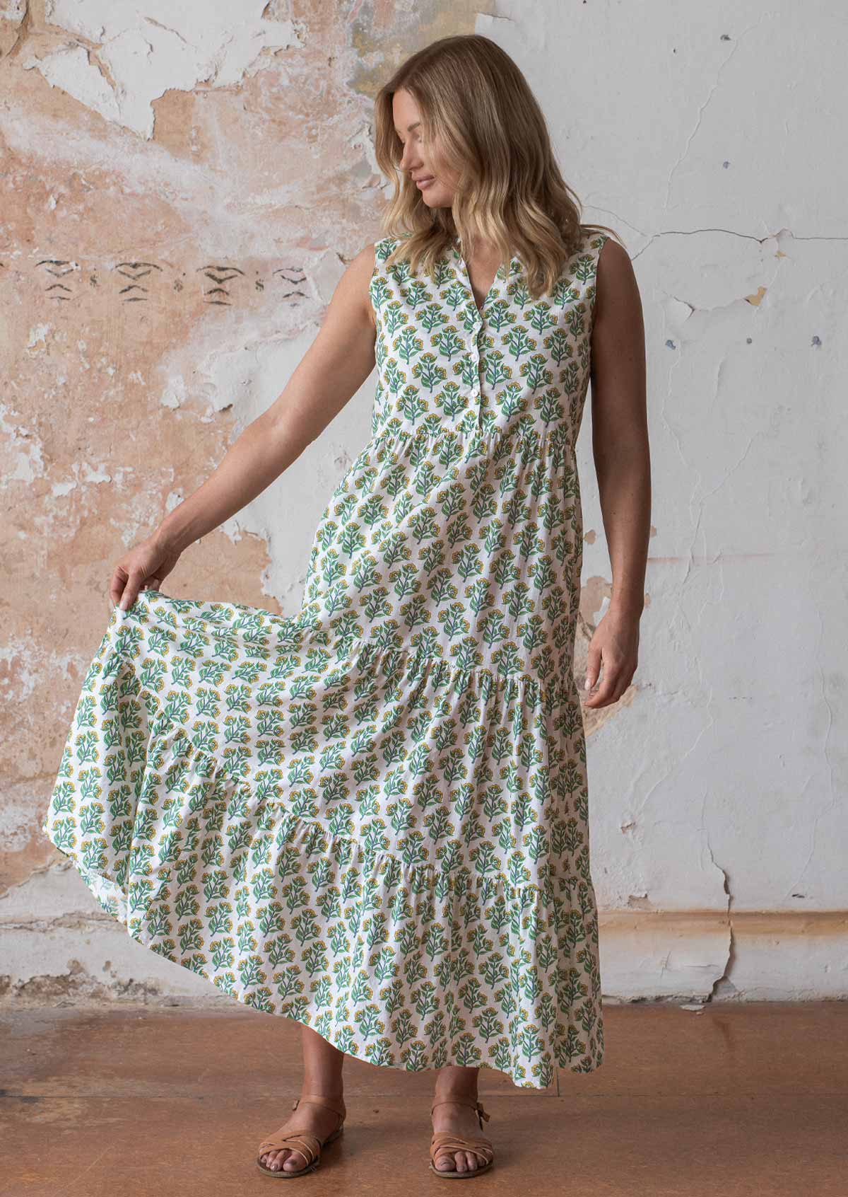 Woman holds skirt out of cotton sleeveless maxi dress with buttoned bodice