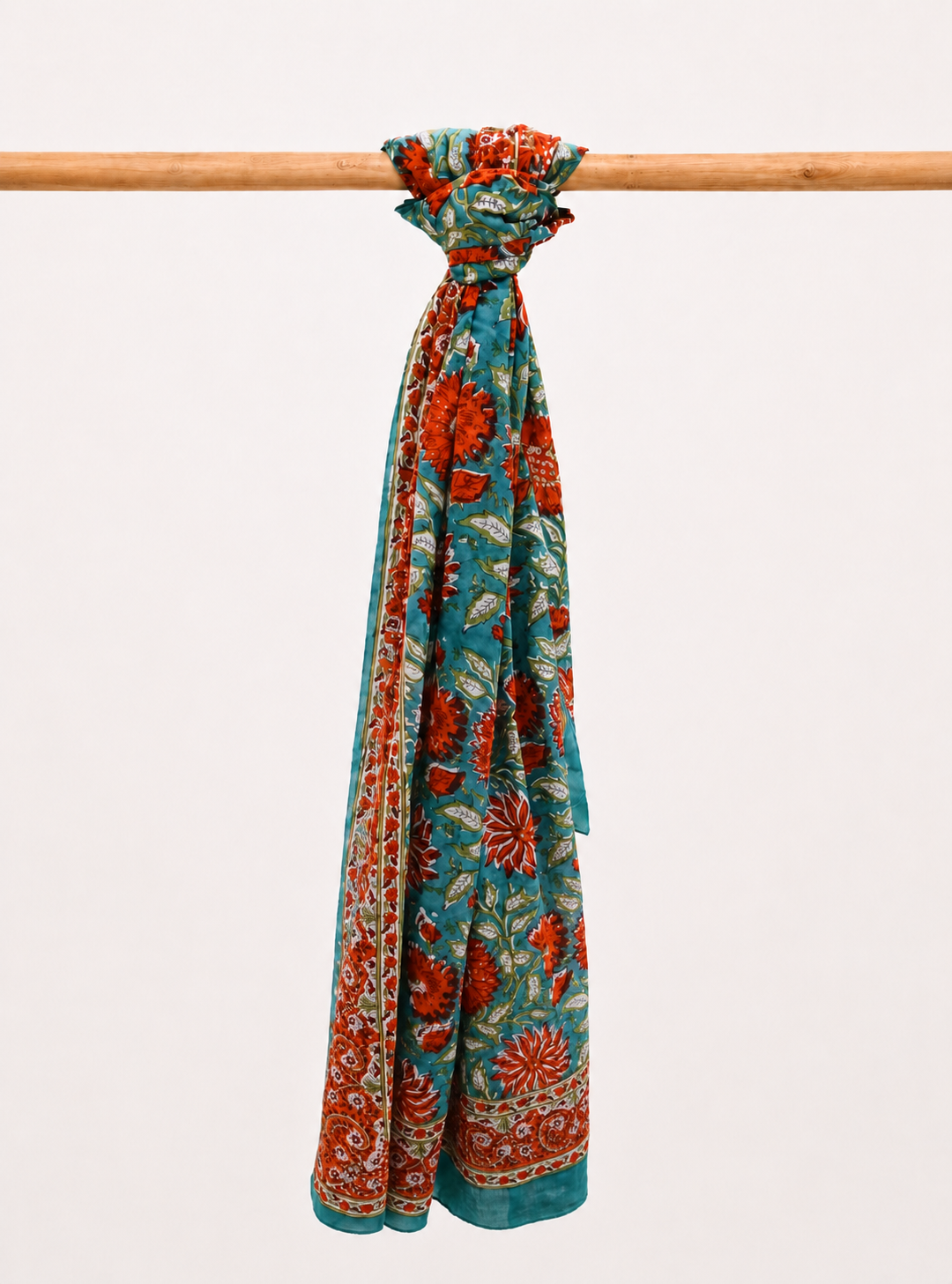 Floral patterned cotton scarf draped over a wooden rod on a light background