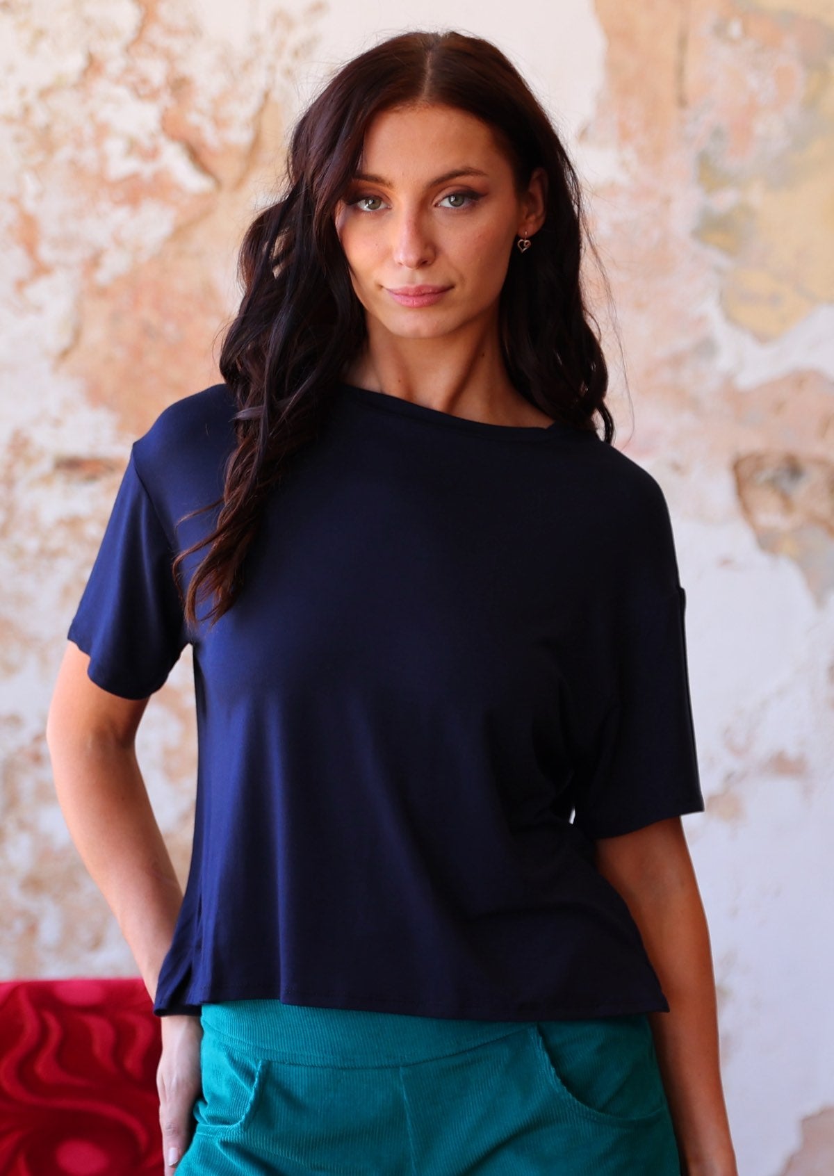 woman in navy blue loose fit t-shirt  over teal corduroy pants 