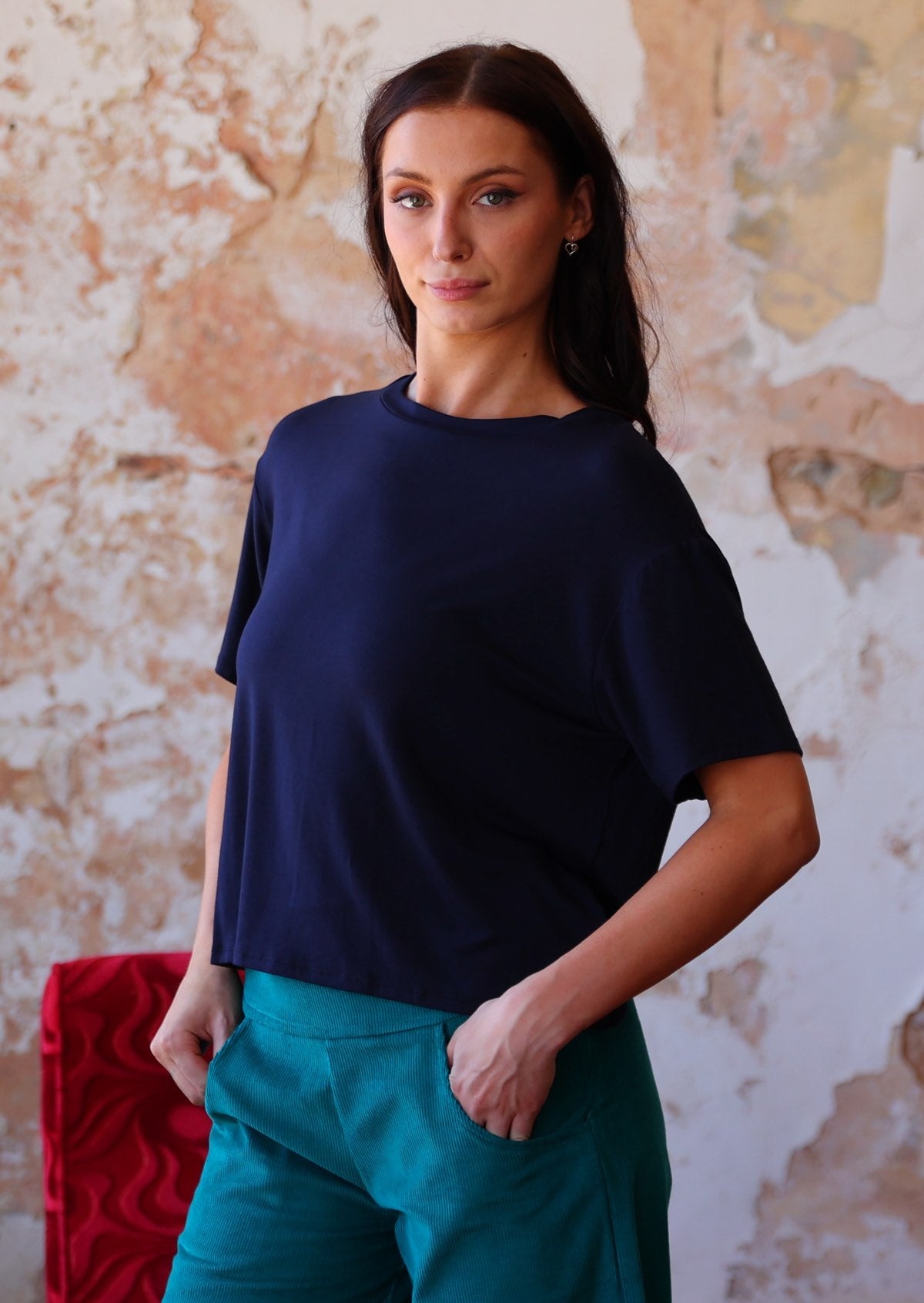 woman in navy blue rayon loose fit t-shirt  over teal corduroy pants 