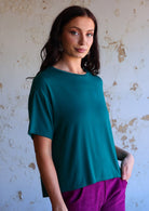 woman wearing loose fit teal blue t-shirt over purple pants