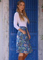 Woman stands side on wearing cotton over the knee length pencil skirt with hand in pocket, paired with a white top