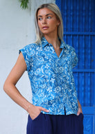 woman with blonde hair in blue cotton button up blouse worn over navy blue cotton pants