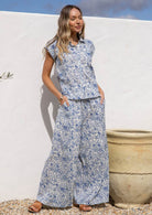 Woman wearing a blue floral print cotton shirt which is 100% cotton against a white background.