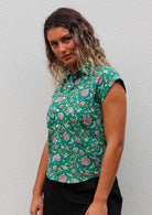 Woman wears cotton collared shirt with shell buttons, in floral print on jade green base