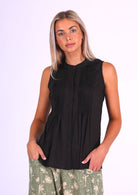 Woman in black sleeveless cotton top that buttons through the front with hidden button and one visible at the front of the neckline