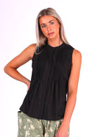 Model poses in black sleeveless cotton top with high round neckline and tiny pleats across bust