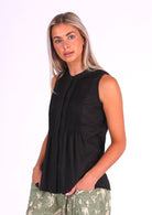 Model wears black sleeveless cotton top that covers the hips, with tiny pleats across bust that make the lower half a relaxed fit