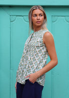 Model poses sideways in cotton sleeveless top that sits over hips, in yellow and green floral print on white base