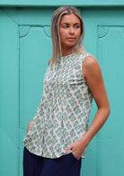 Model poses sideways in sleeveless cotton top with yellow and green floral print on white base, with hidden central buttons