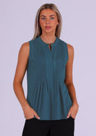 Woman in blue sleeveless cotton top that buttons through the front with hidden button and one visible at the front of the neckline