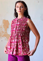 Woman in pink floral cotton sleeveless blouse with pin tucks on front 